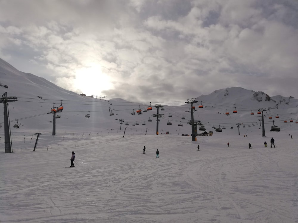 people riding ski lift on snow covered mountain during daytime