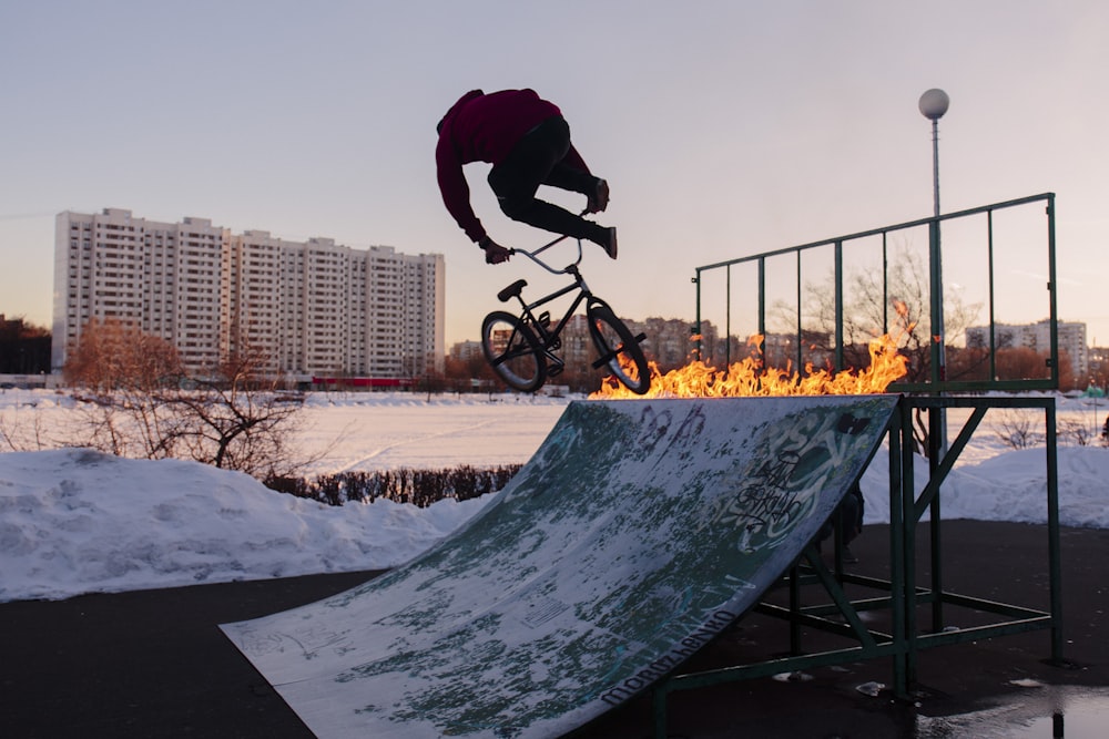 man in black jacket and pants riding on black bicycle on snow covered ground during daytime