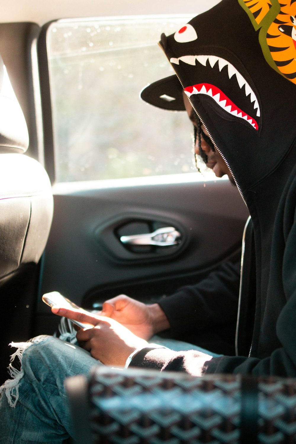 person in black and red fitted cap and blue denim jacket driving car during daytime