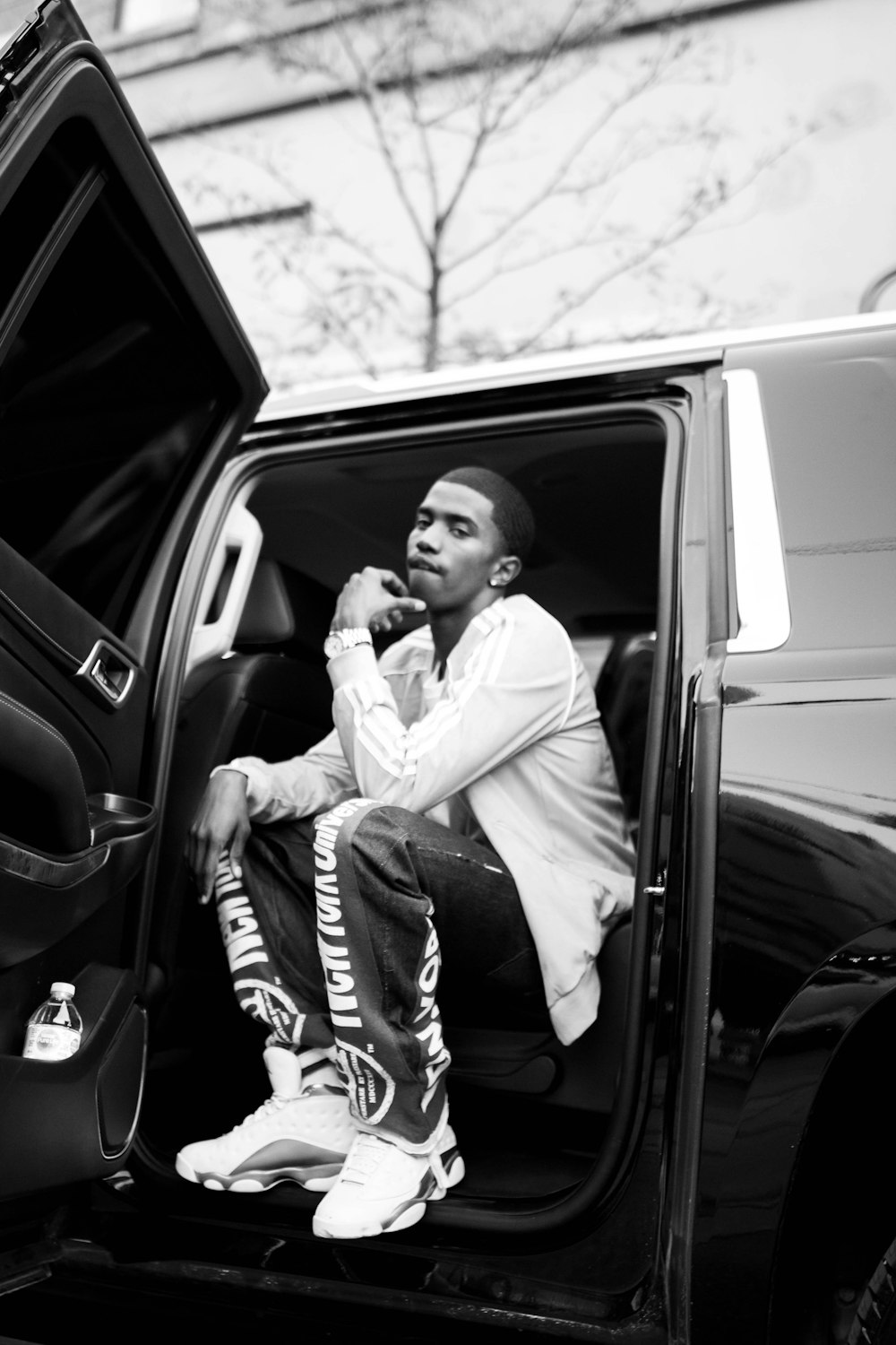 man in white dress shirt and pants sitting on car seat in grayscale photography