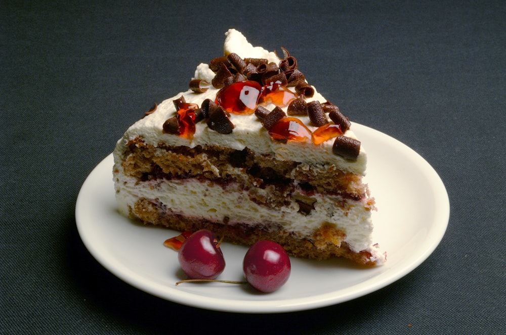 sliced cake with cherry on white ceramic plate