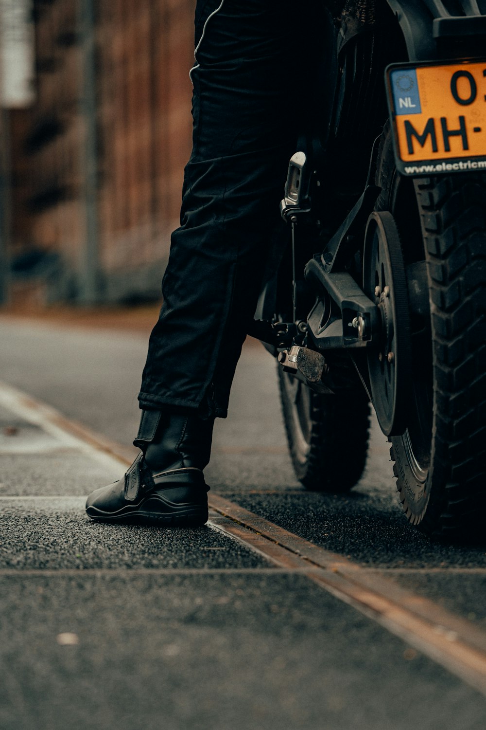 person in black leather boots riding motorcycle on road during daytime