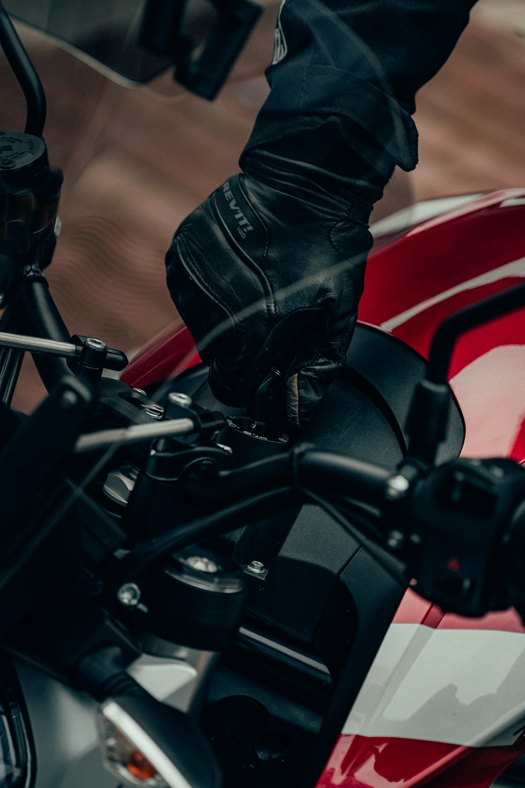 person in black leather boots riding on black and red motorcycle