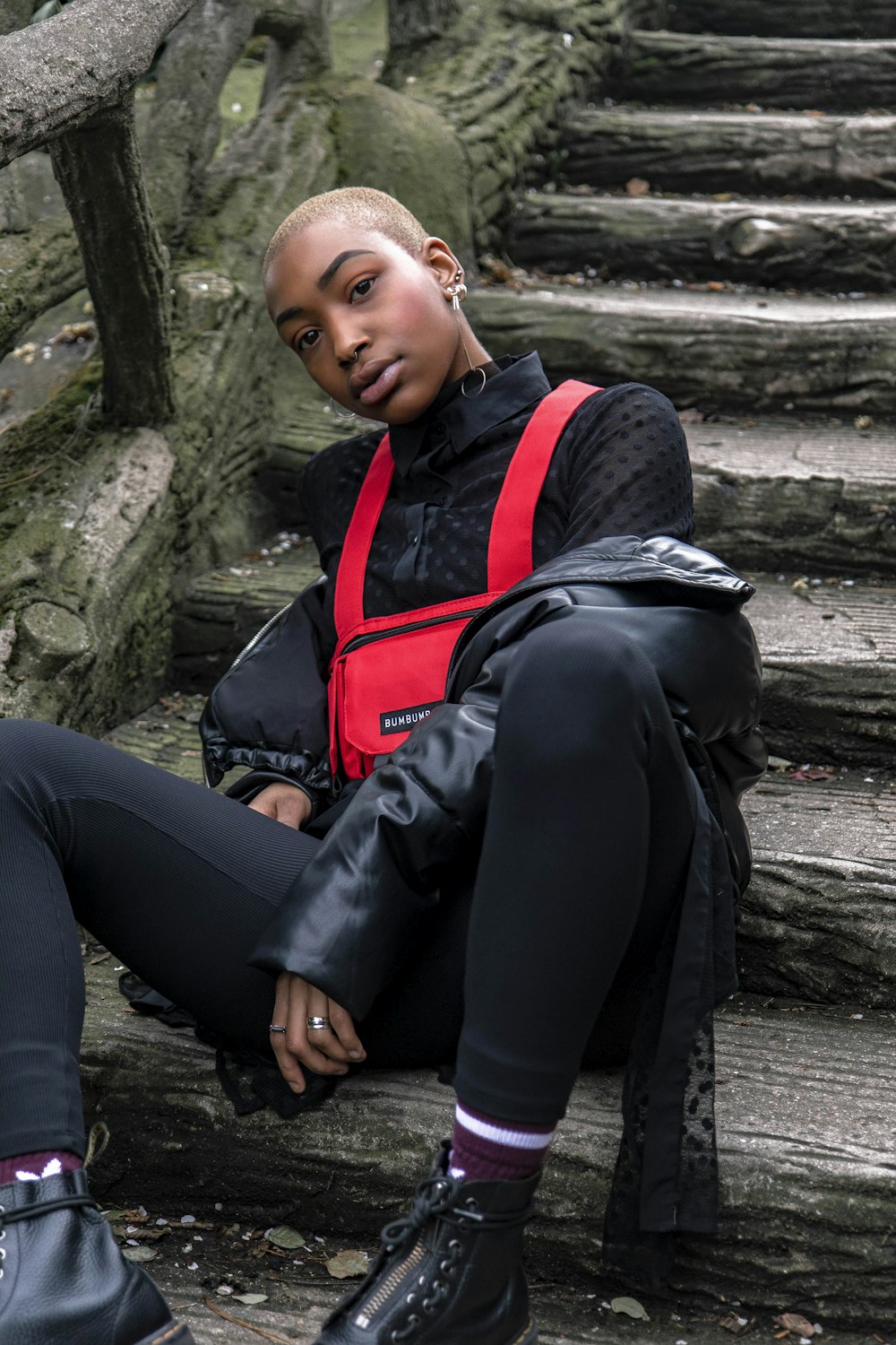 woman in black jacket and black pants sitting on gray concrete stair