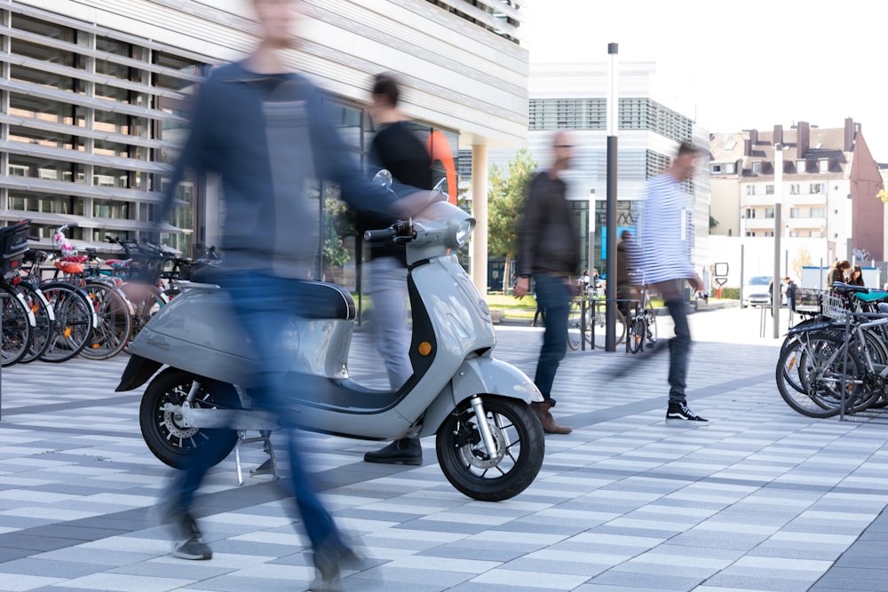 Mann im schwarzen Anzug fährt auf blauem Motorroller