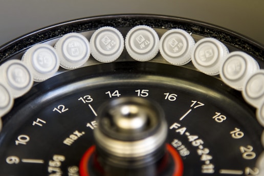 Circular arrangement of small, sealed containers placed around the edge of a black, numbered disk, typically found in laboratory equipment such as a centrifuge.