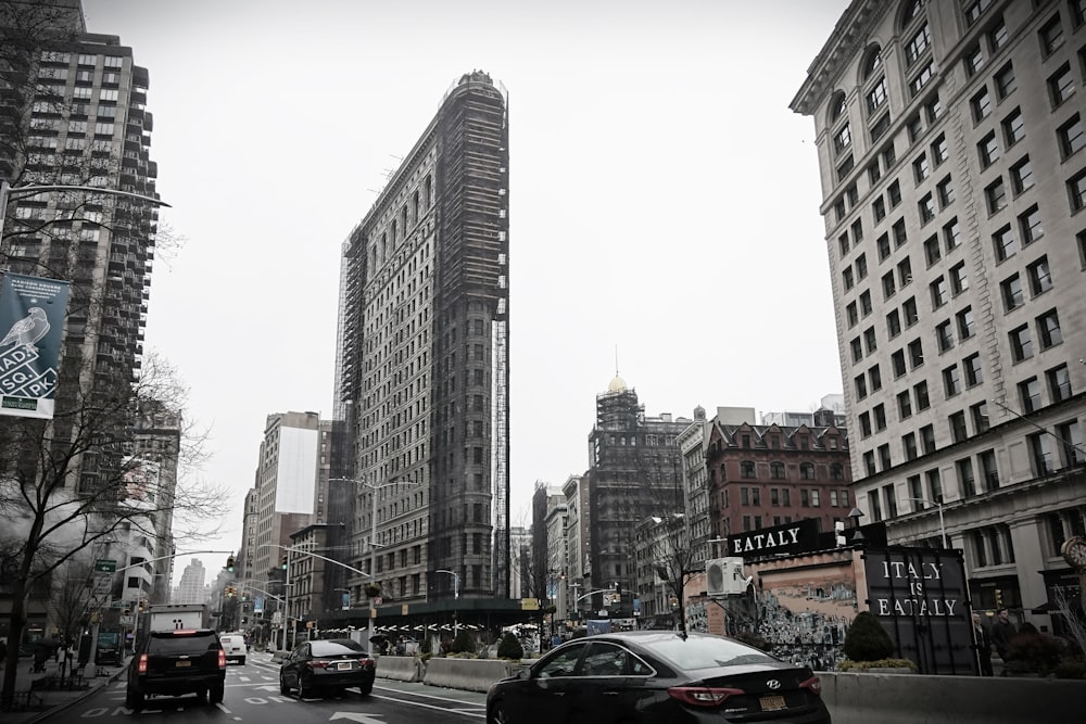 cars parked on side of road near high rise buildings during daytime