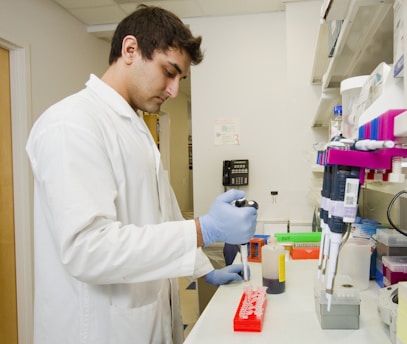 Biomédico dentro de um laboratório de análises clínicas, fazendo alíquotas com uma pipeta