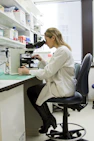 Scientist using a microscope for laboratory research and pathology analysis.