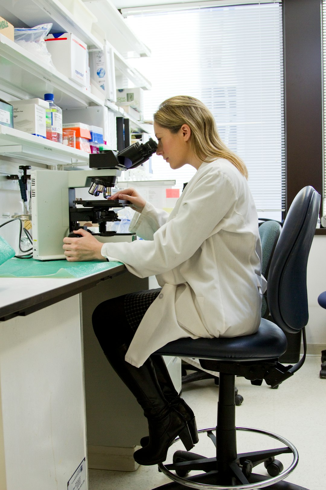 A female scientist in a laboratory looks through a microscope.