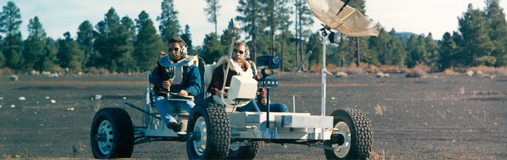 2 men and 2 women riding on white and blue atv during daytime