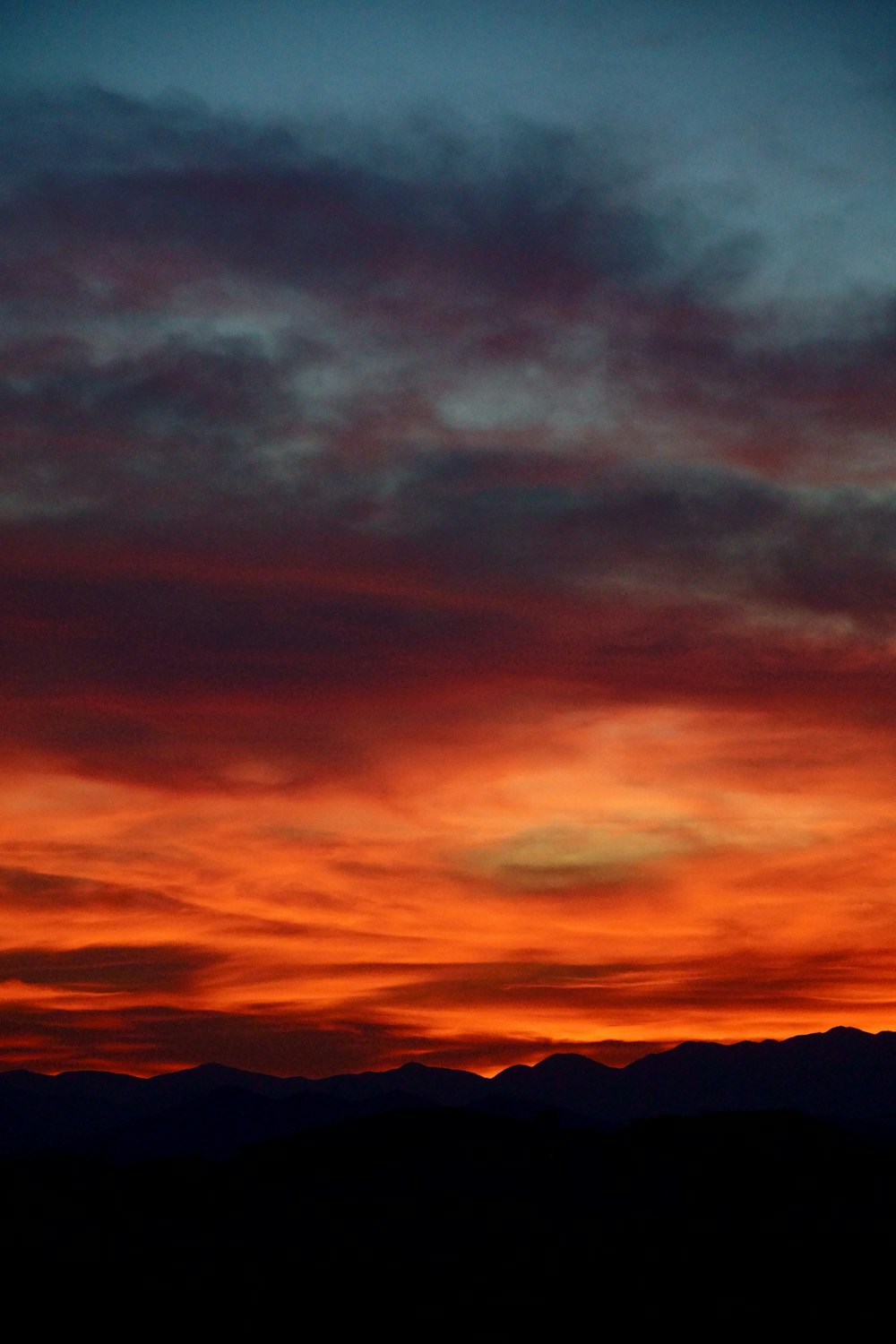 Silhouette de montagnes sous un ciel nuageux au coucher du soleil