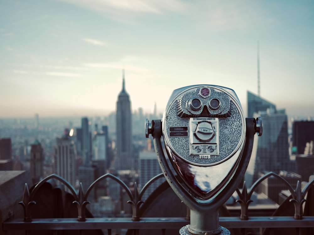 gray coin operated telescope across city buildings during daytime