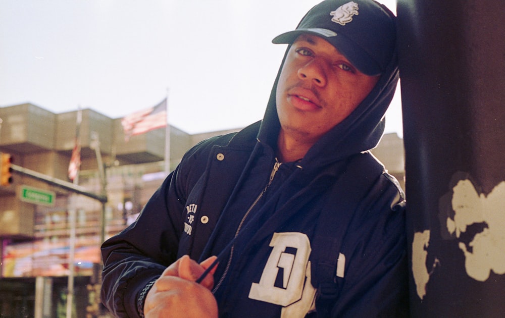 man in black and white hoodie wearing black cap