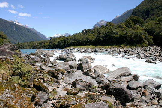 rocky shore with green mountains in the distance in Haast New Zealand