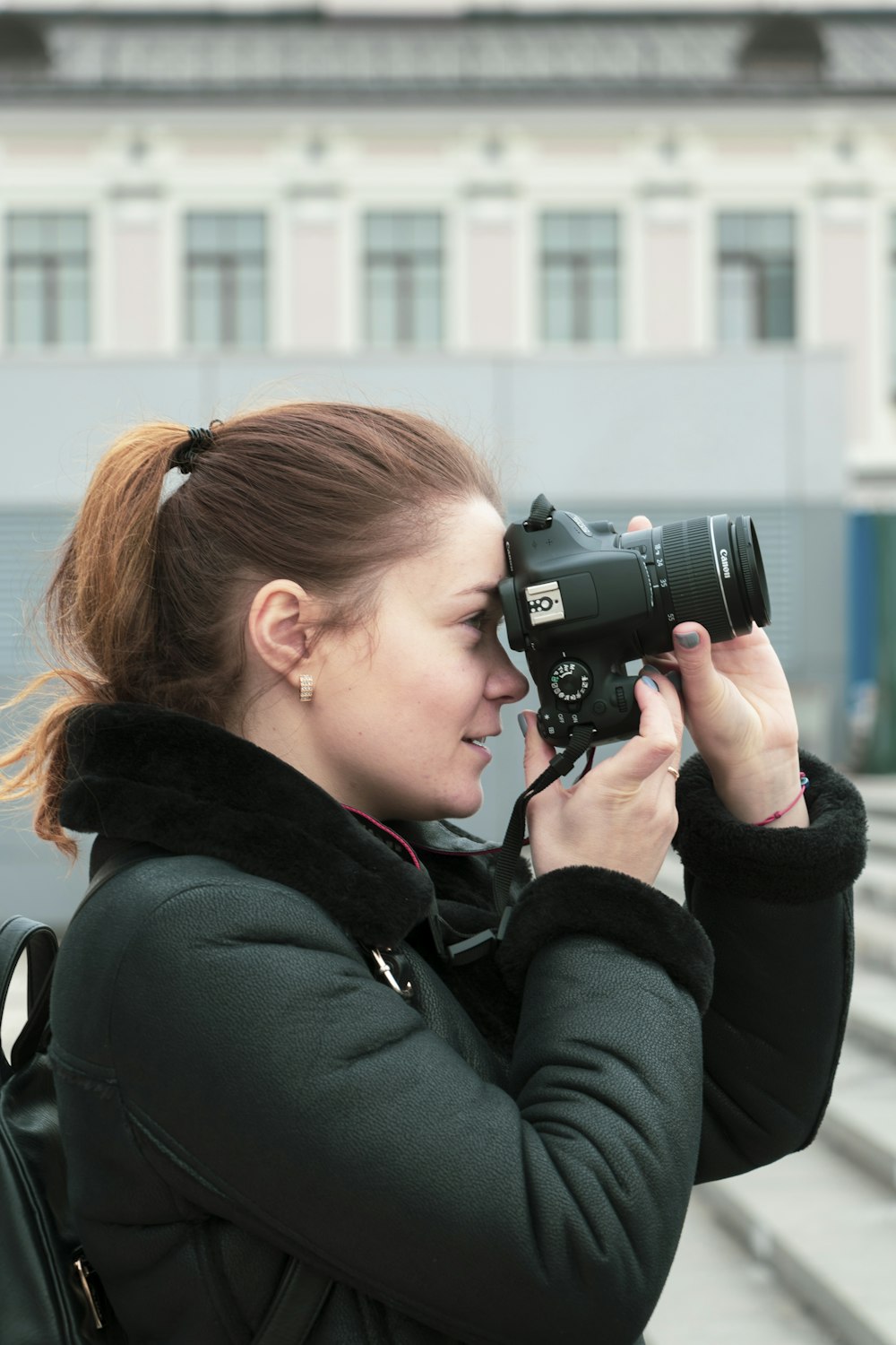 woman in black jacket holding black dslr camera