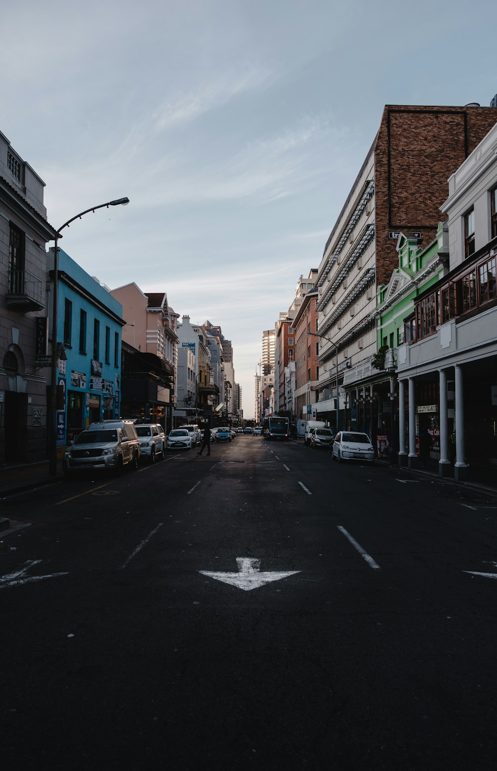 cars parked on side of the road in between buildings during daytime