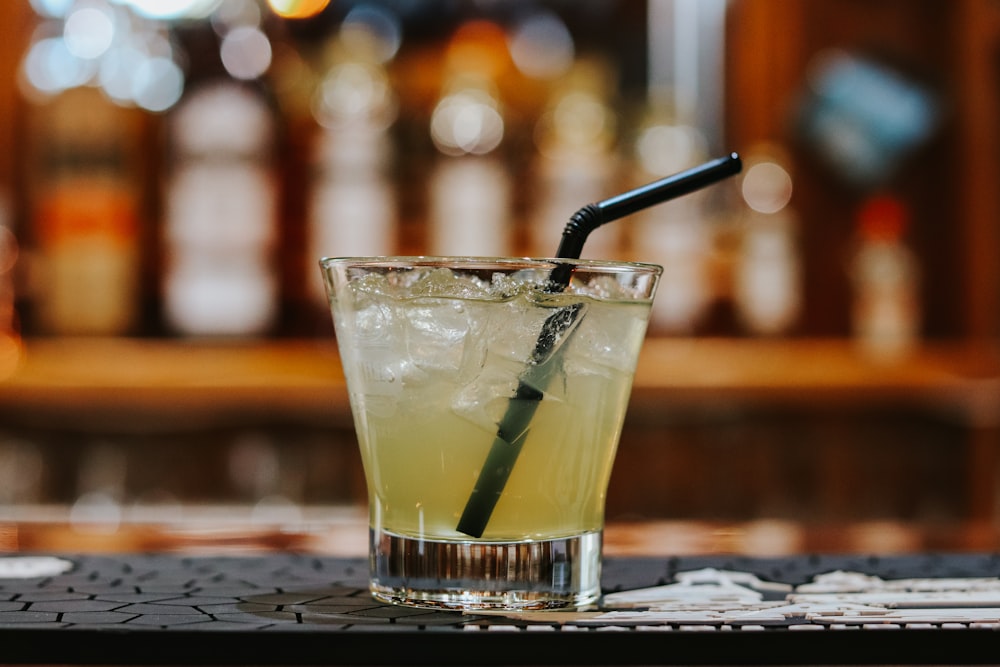 clear drinking glass with yellow liquid and black straw