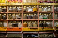 Glass jars filled with assorted whole spices lined up on a kitchen shelf.