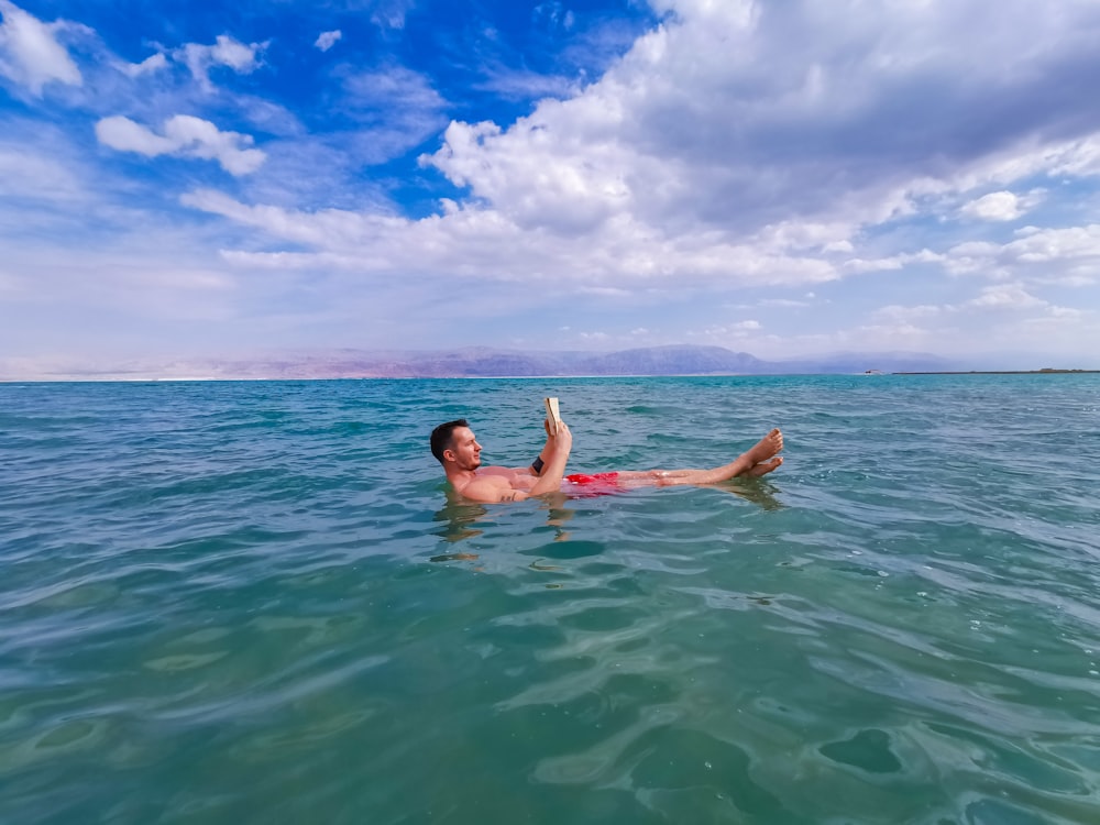 Frau im blau-weißen Bikini schwimmt tagsüber im Meer