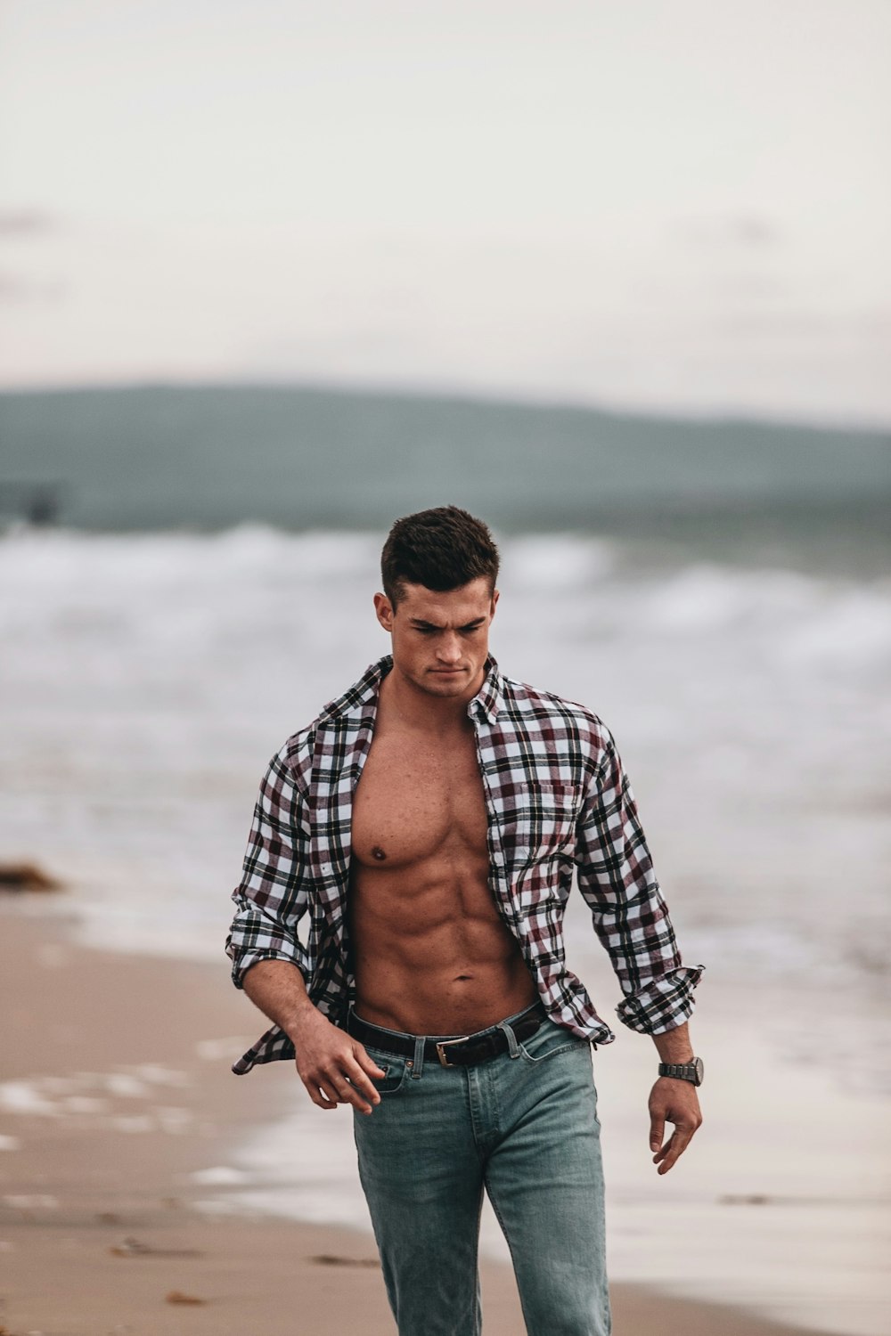 man in black and white checkered dress shirt and blue denim jeans standing on shore during