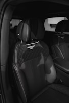 A close-up shot of luxurious car seats featuring a quilted leather design and prominent branding emblem embossed on the headrest. The seats are upholstered with high-quality materials and have detailed stitching, contributing to an elegant and sophisticated interior.