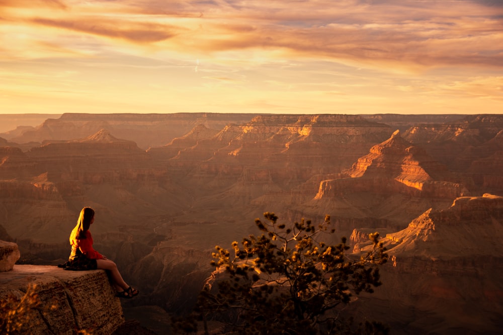 woman in red shirt sitting on rock formation during daytime