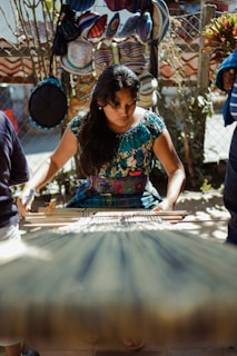 Guatemalan in blue green and yellow floral dress sitting on chair