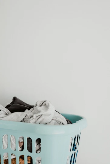 Fresh laundry basket filled with soft, clean clothes beside a bottle of detergent