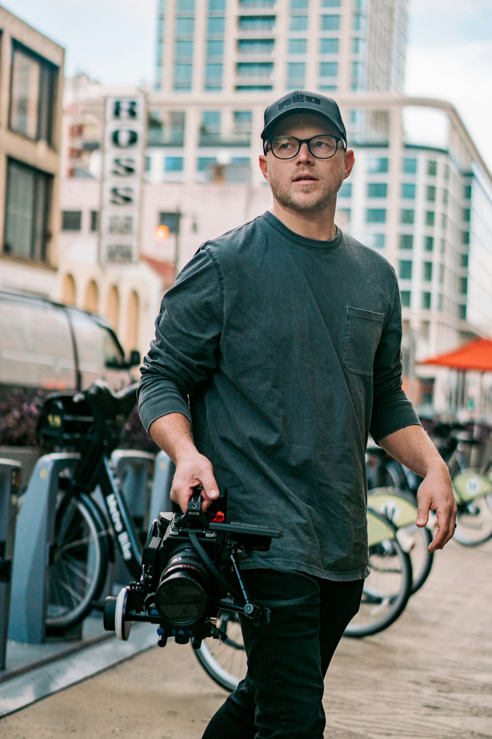 Homme en chemise à manches longues noire et lunettes de soleil noires debout à côté d’un vélo noir pendant la journée