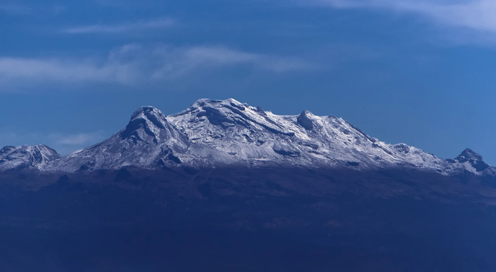 Snow-covered peaks of Iztaccíhuatl under a blue sky