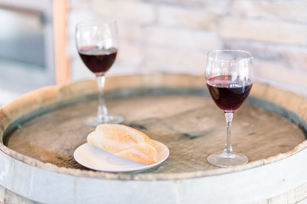 taça de vinho transparente com vinho tinto na mesa de madeira marrom