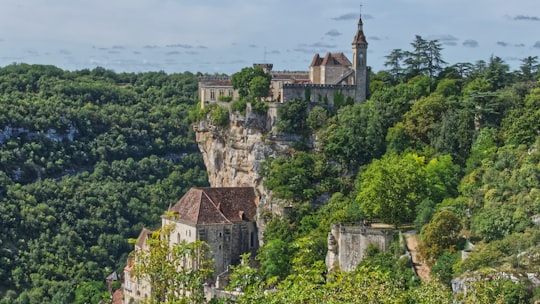 green trees near brown concrete building during daytime in Causses du Quercy Natural Regional Park France