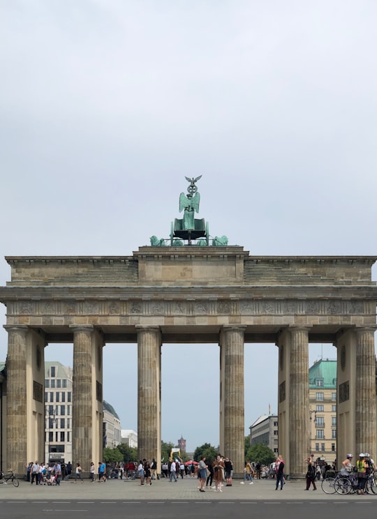 statue of man riding horse on top of building in Brandenburg Gate Germany
