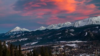 snow covered mountain under orange and gray cloudy sky