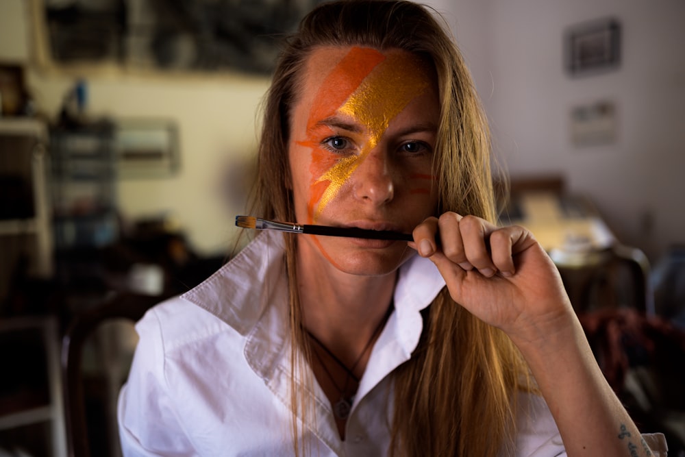 woman in white button up shirt holding brown paint brush