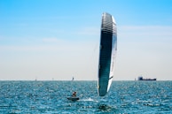people riding on white and blue sail boat on sea during daytime