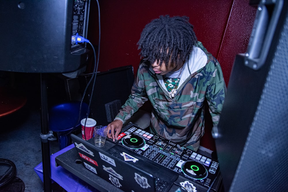 man in green and brown camouflage jacket playing dj controller