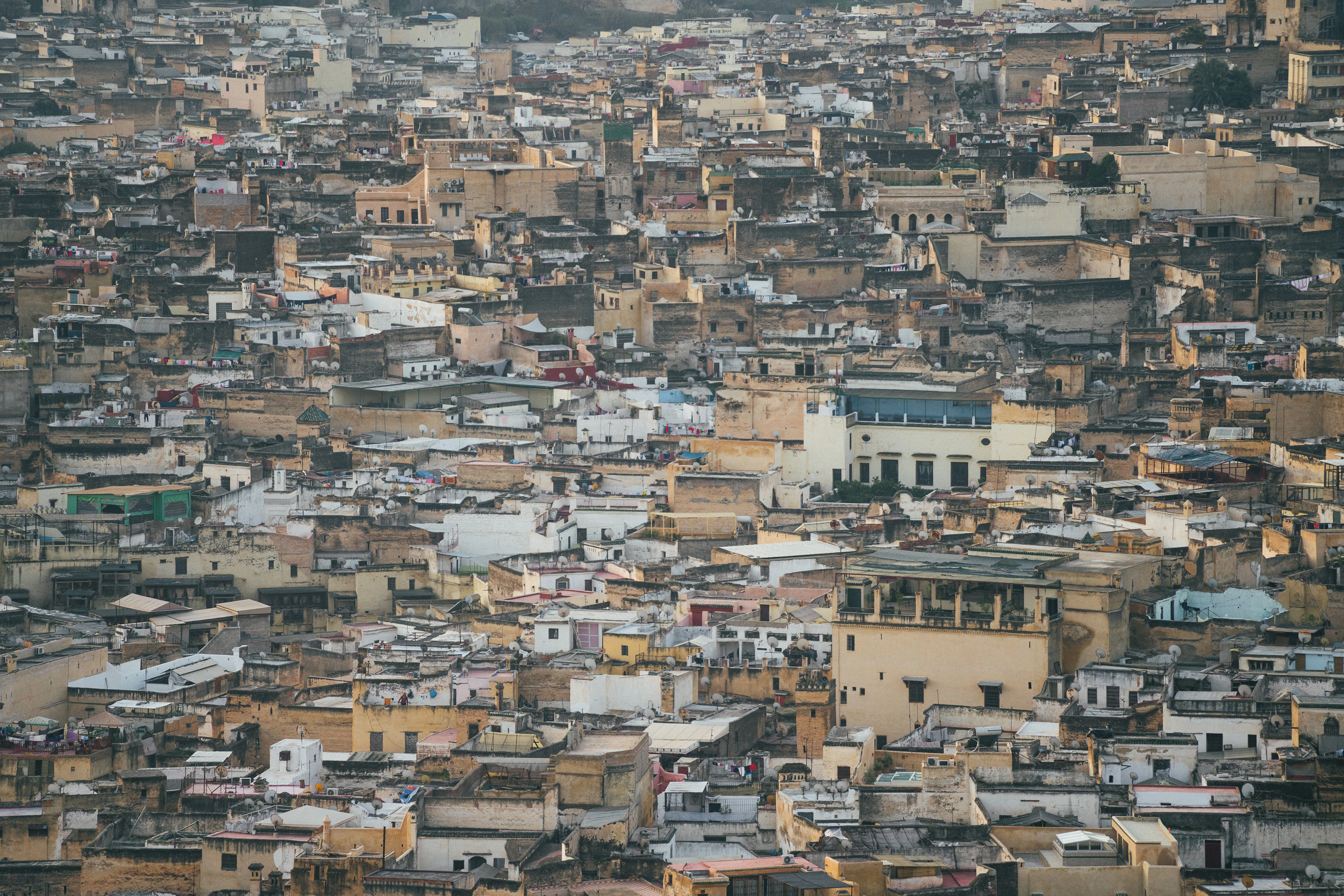 Densely packed earth-toned rooftops and terraces of the medina of Fez, Morocco, seen from the surrounding hills