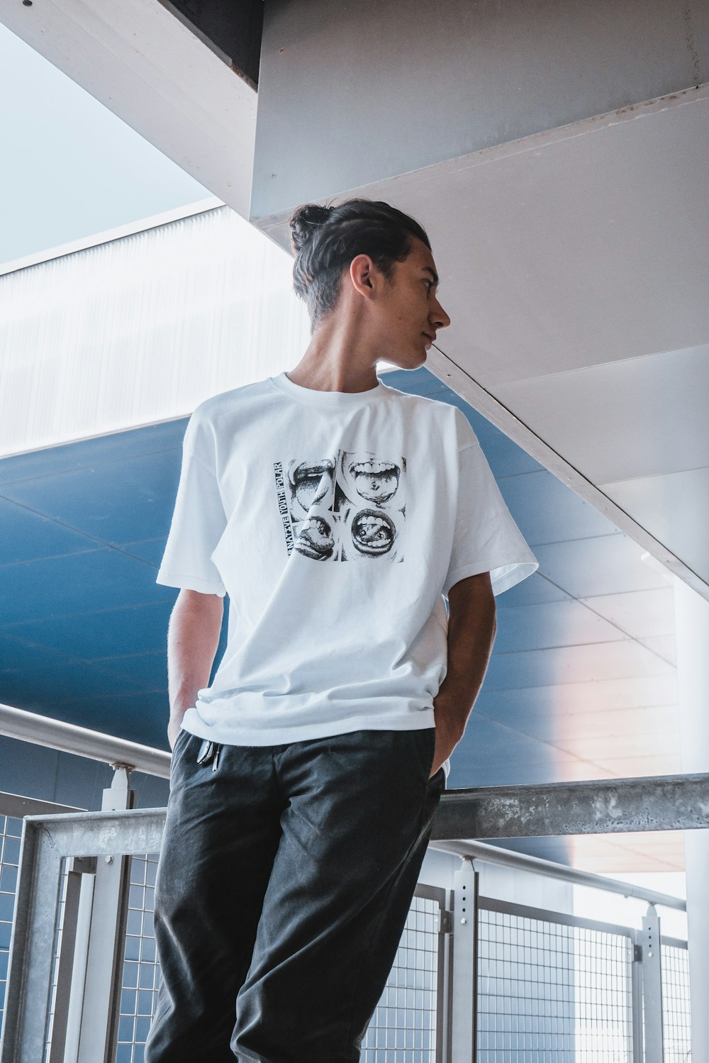 man in white crew neck t-shirt and black pants standing on white concrete stairs