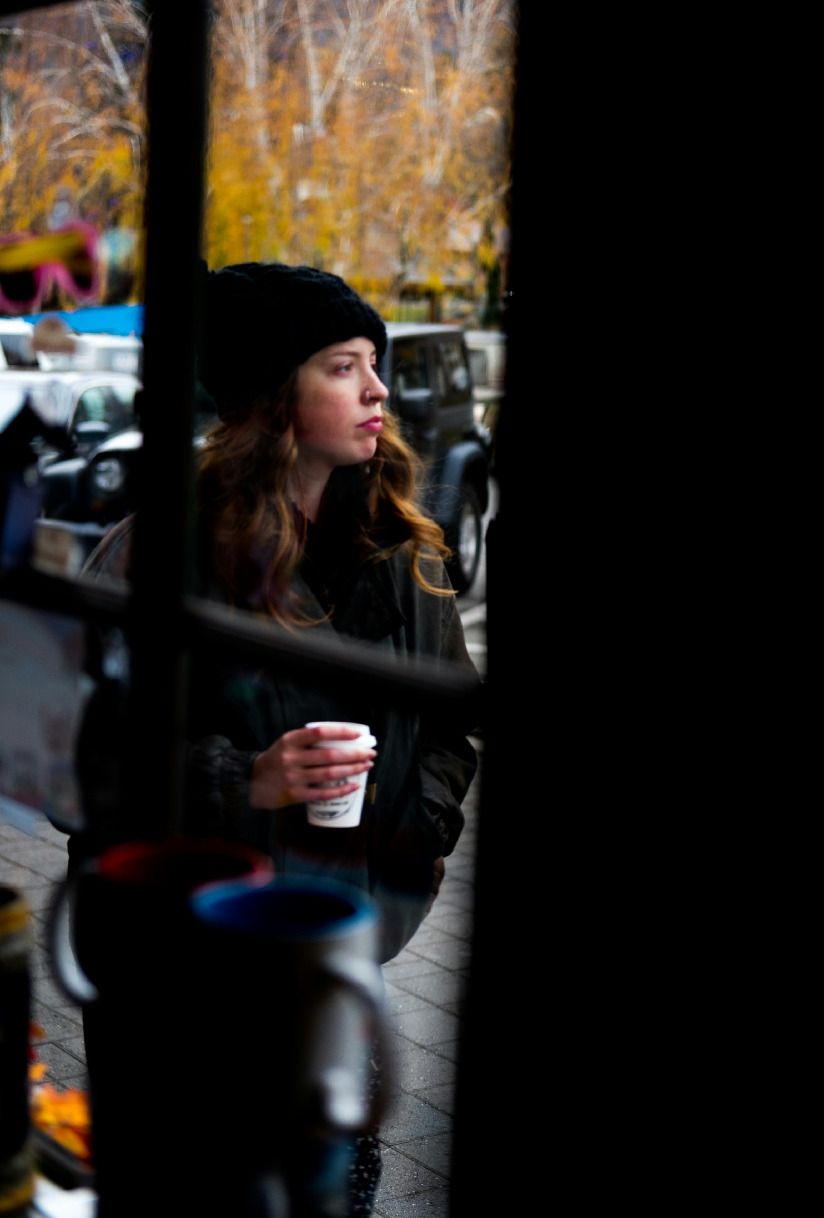 woman in black knit cap holding blue ceramic mug