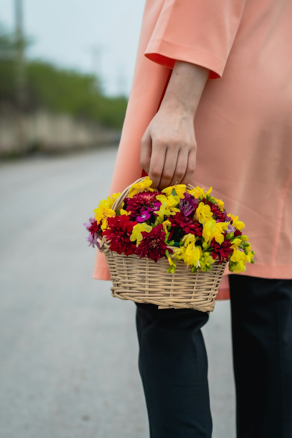 woman in orange dress holding yellow and pink flower bouquet