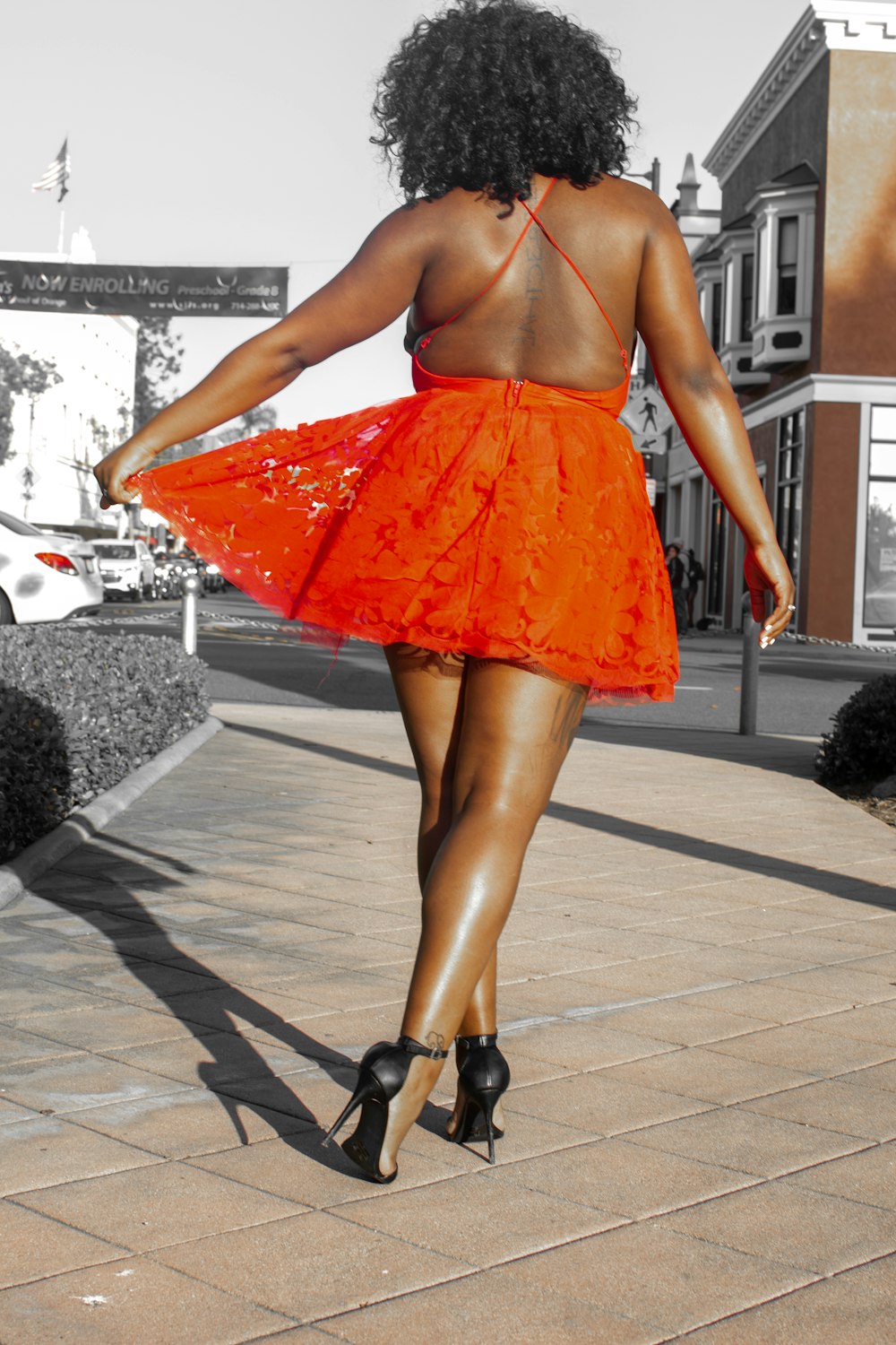 woman in orange skirt standing on gray concrete floor during daytime