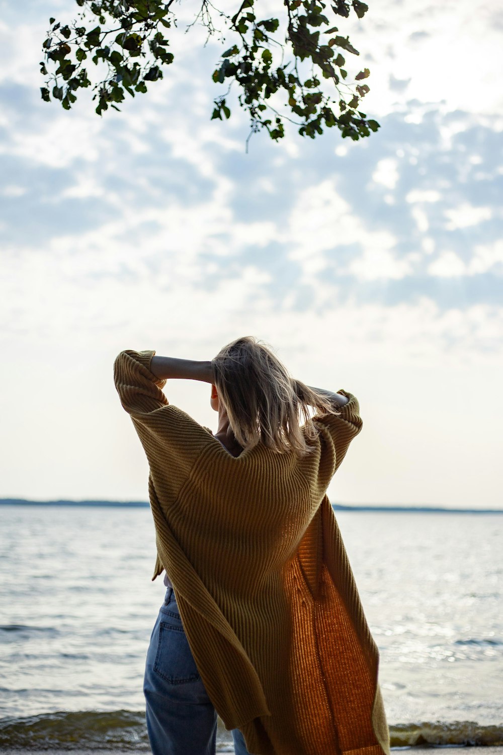 woman in brown long sleeve shirt standing near body of water during daytime