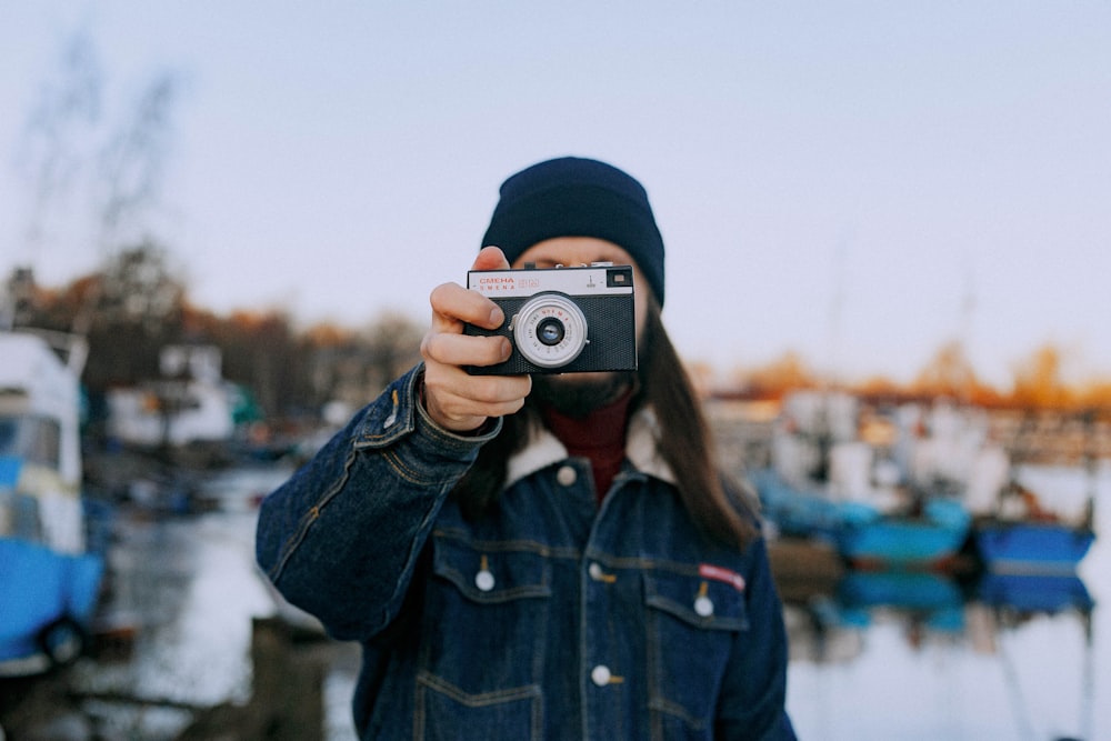 woman in blue denim jacket holding camera