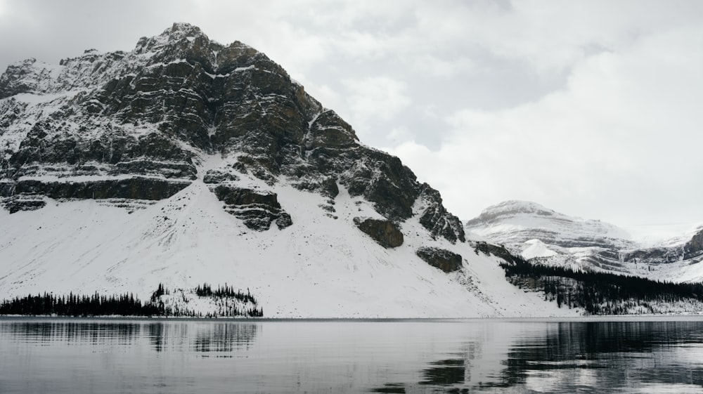 snow covered mountain near body of water during daytime