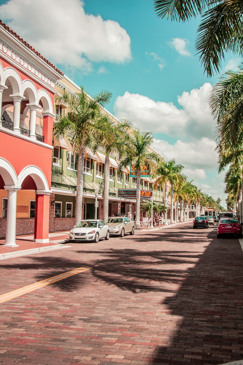 cars parked in front of white and red concrete building during daytime