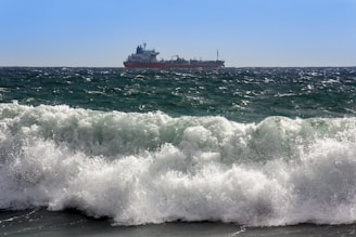 A cargo ship sailing across the ocean under clear skies.
