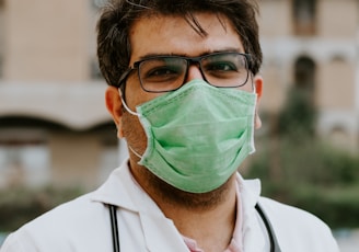 man in white scrub suit wearing green mask