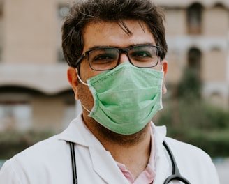 man in white scrub suit wearing green mask